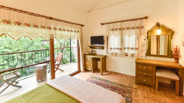 A bedroom with a balcony, a wooden desk, a television, and a mirror. - Piramit Hotel (Fethiye)