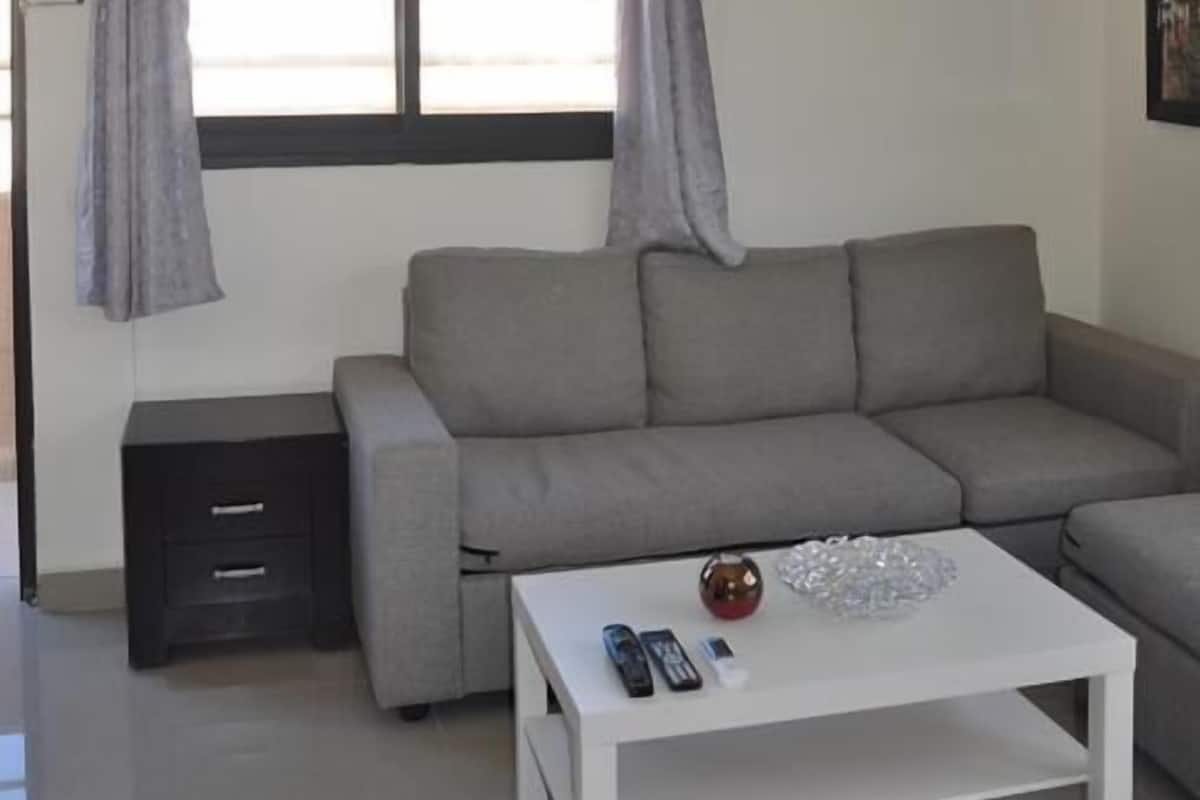 A living room with a grey sofa, a white coffee table, and a small black side table.