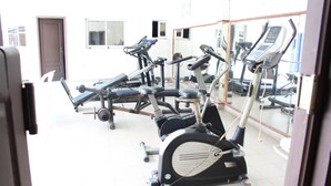 A gym with various exercise machines, a door, and a window. - Jet Hôtel (Douala)
