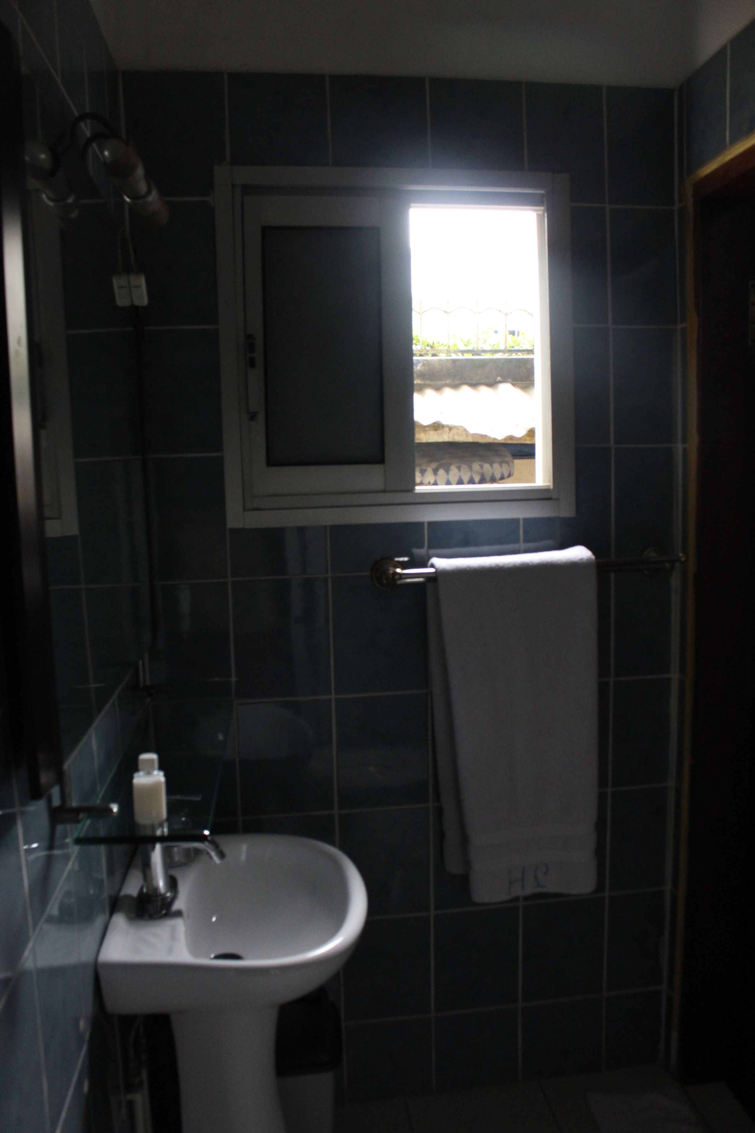 Un baño con lavamanos, ventana y toallero.