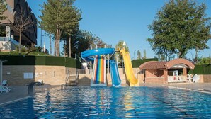 A swimming pool with multiple slides, a covered seating area, and trees in the background. - Fimar Life Thermal Resort Hotel (Göynücek)