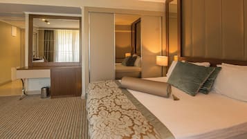 A hotel room with a large bed, a bedside table, a mirror, and a small desk area.