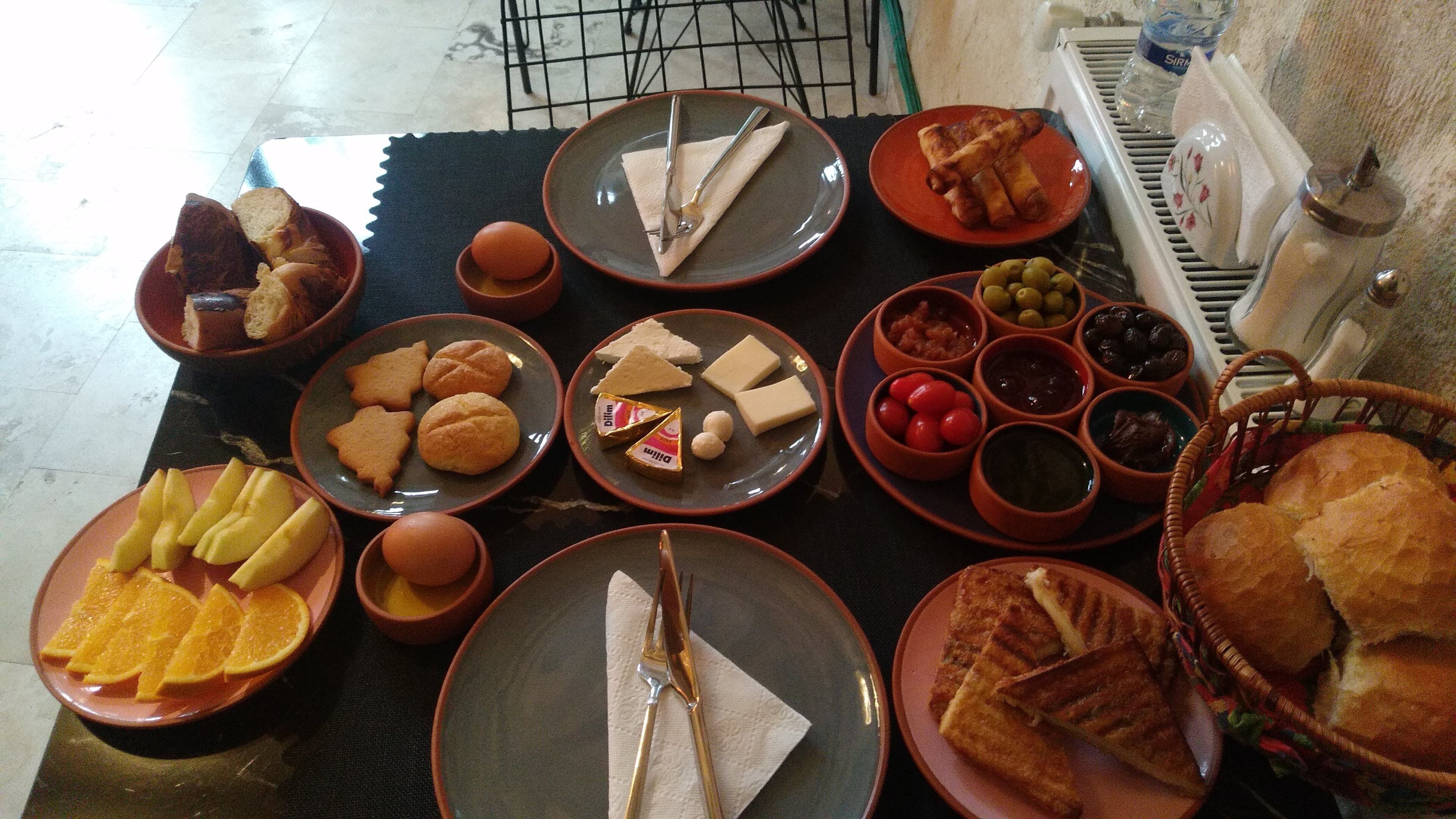 A table with various food items and utensils, including bread, cheese, and olives.