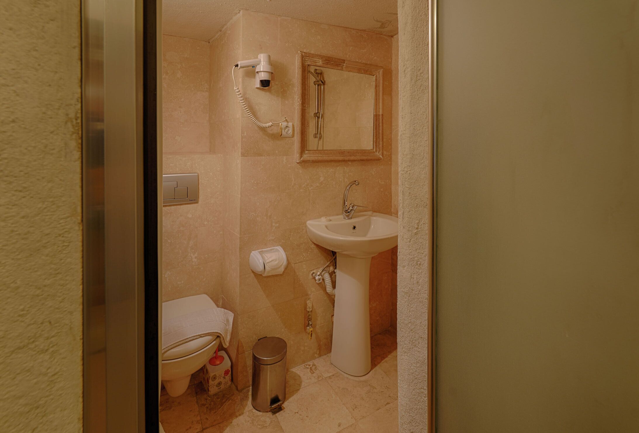 Un baño con inodoro, lavamanos, cubo de basura, secador de pelo y ducha.