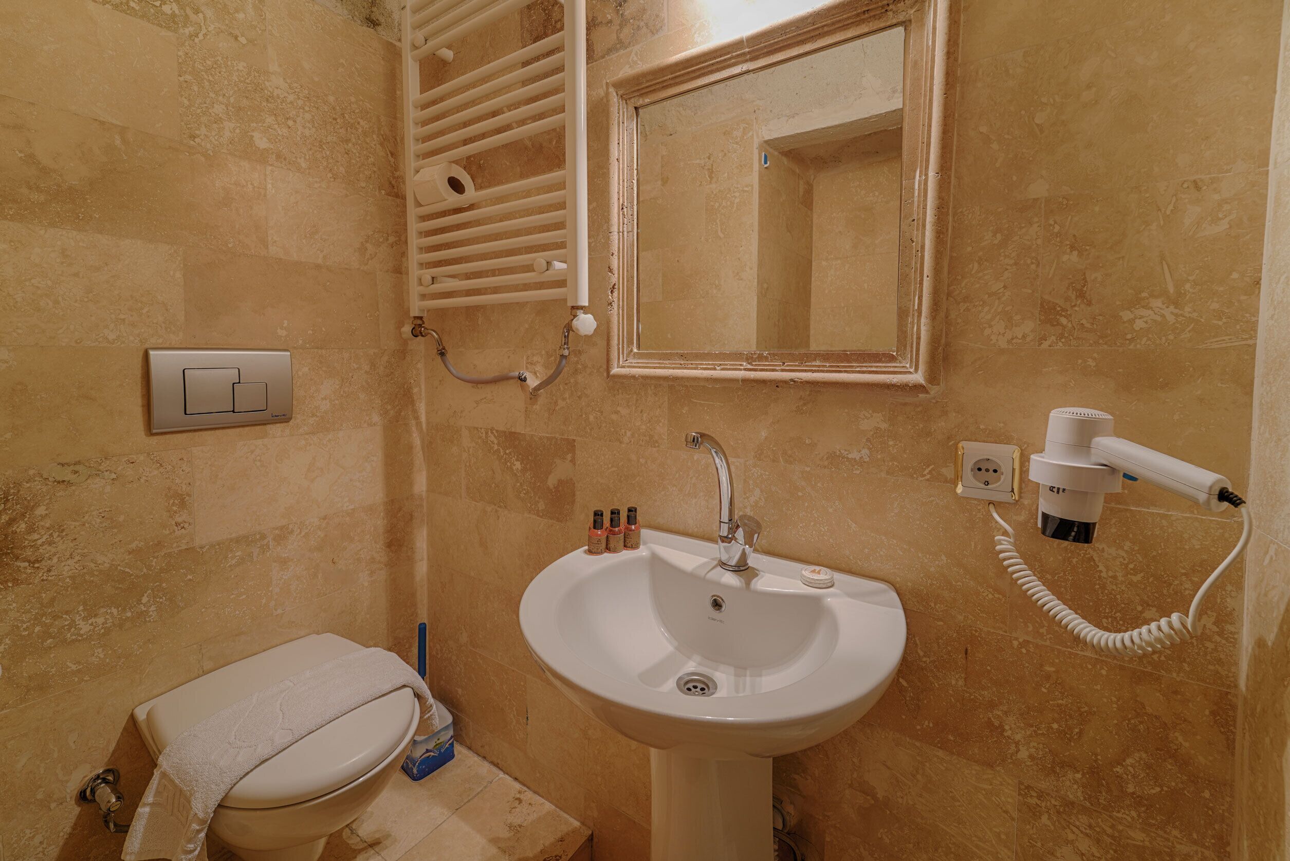 A bathroom with a sink, mirror, towel rack, and hairdryer.