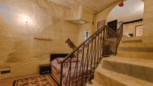 A bedroom with a bed, a wooden floor, a marble staircase, and a red hanging light. - Avlu Cave House  (Nevsehir)