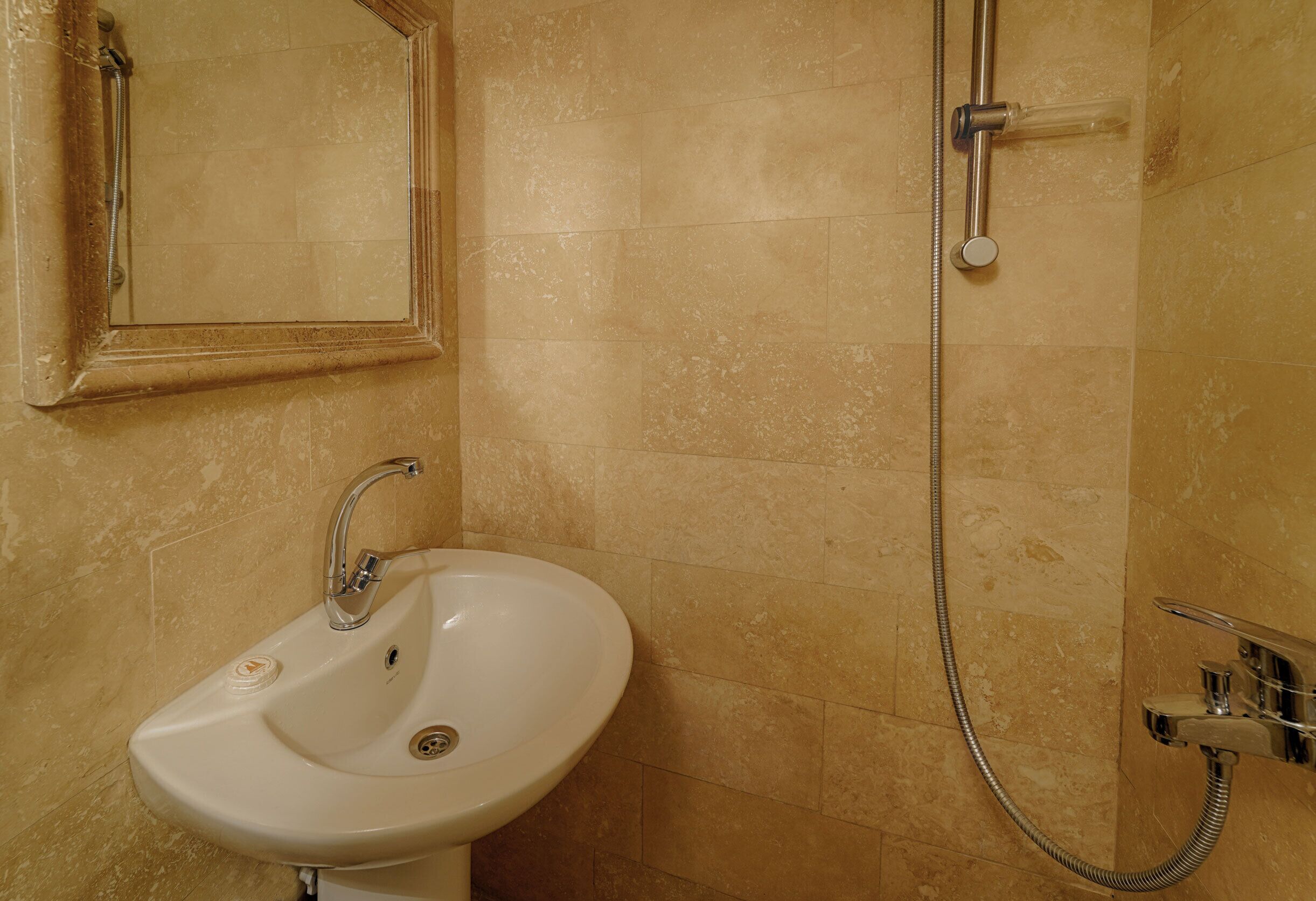 A bathroom with a sink, mirror, and shower.
