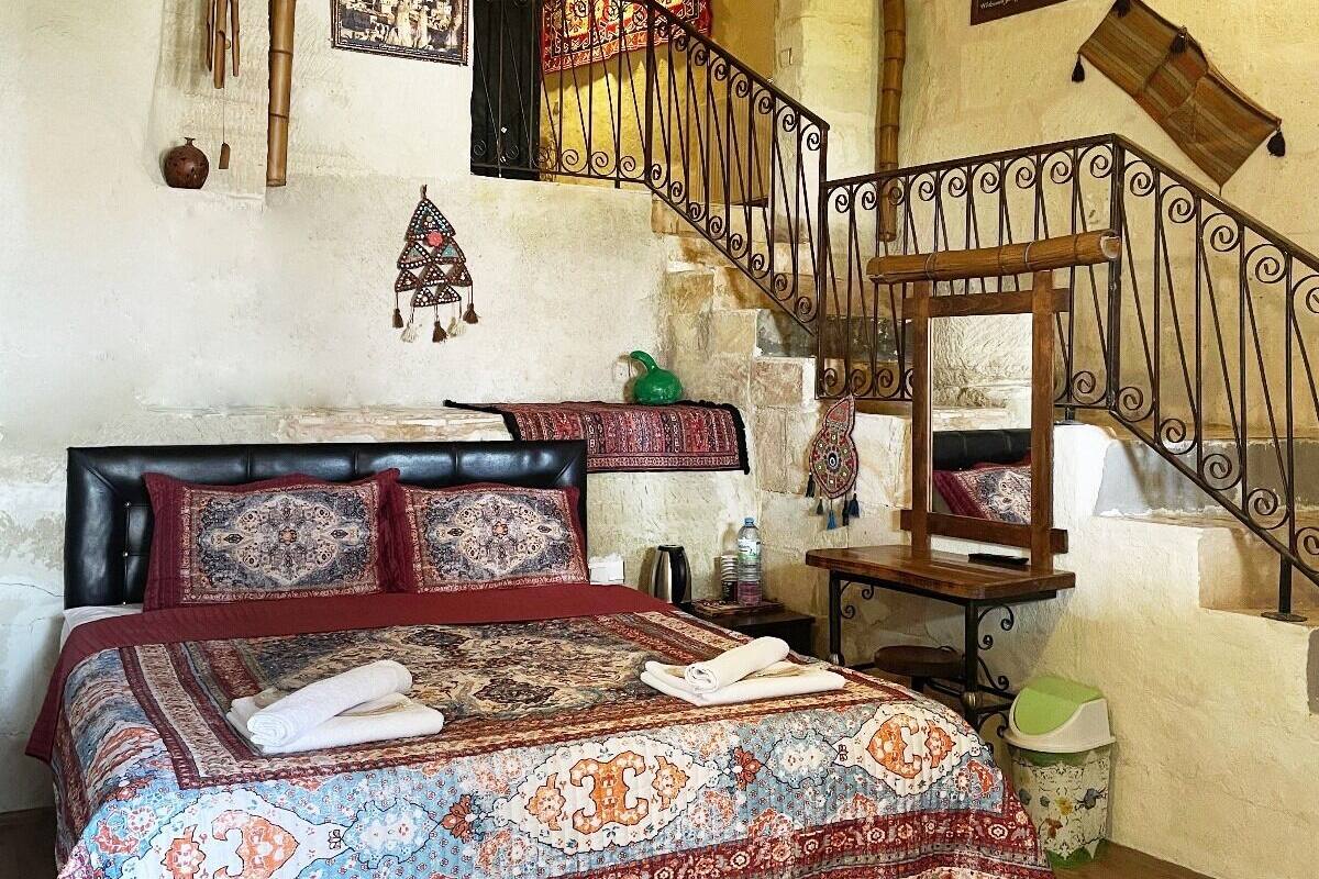 Una habitación tradicional con una cama, una escalera de madera y una pequeña mesa.