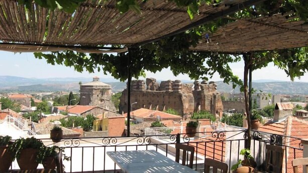 A terrace with a view of historic stone walls and buildings. - Odyssey Guest House (Bergama)
