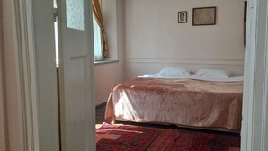 A bedroom with a bed, a window with curtains, and two framed pictures on the wall. - Odyssey Guest House (Bergama)