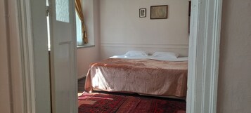 Un dormitorio con una cama, una ventana con cortinas y dos cuadros en la pared.