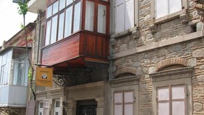 A traditional building with a stone facade, wooden balconies, and a sign indicating a guest house. - Odyssey Guest House (Bergama)