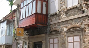 Un edificio tradicional con fachada de piedra, balcones de madera y un letrero que indica una casa de huéspedes.