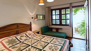 Un dormitorio con cama de madera, una silla verde, una ventana con cortinas y una colcha en la cama.