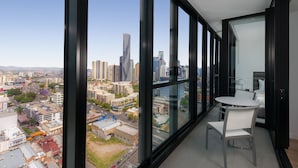 A modern room with large windows offering a city view, a small round table, and two chairs.