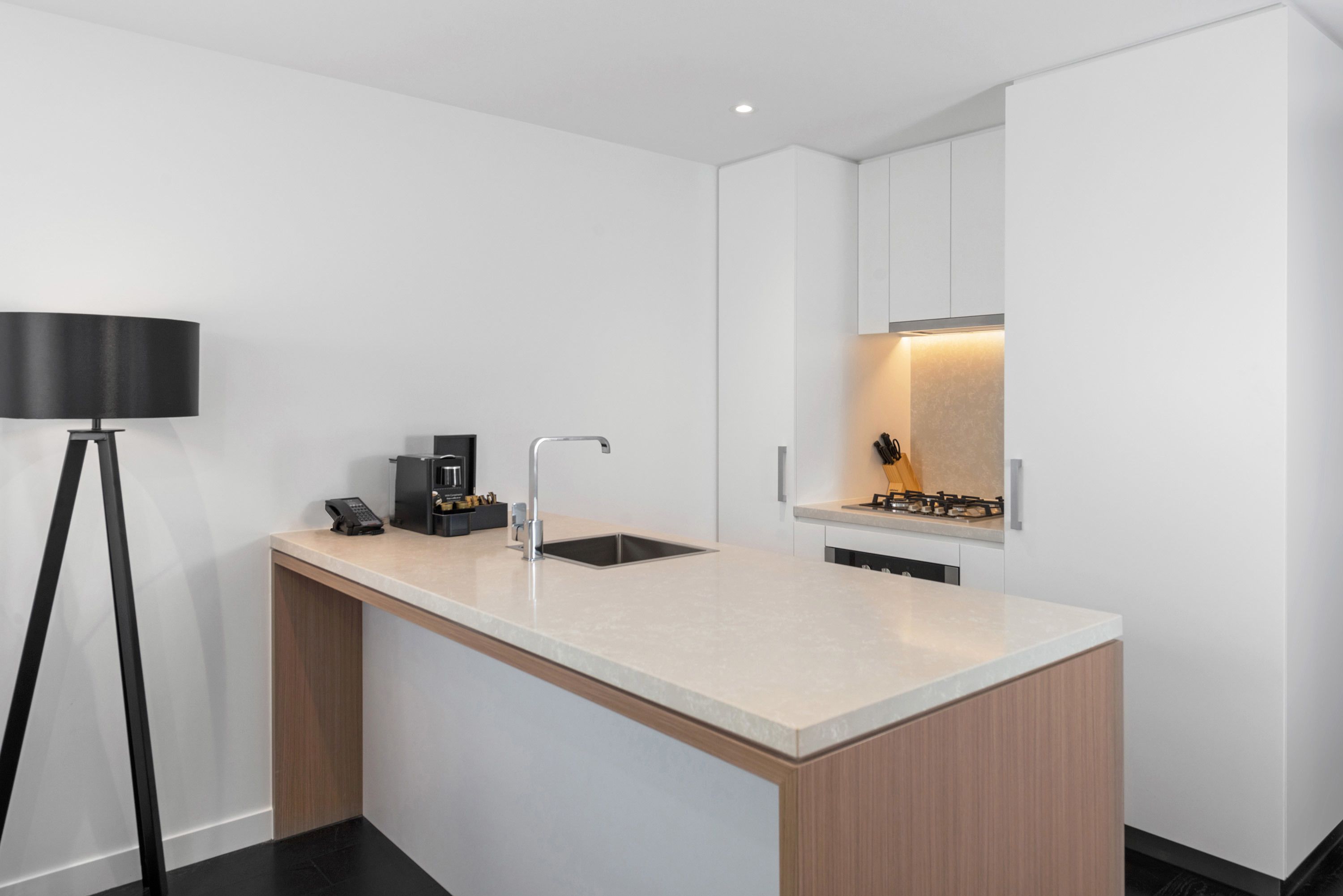 A modern kitchen with a central island, a coffee machine, a sink, and a gas stove.