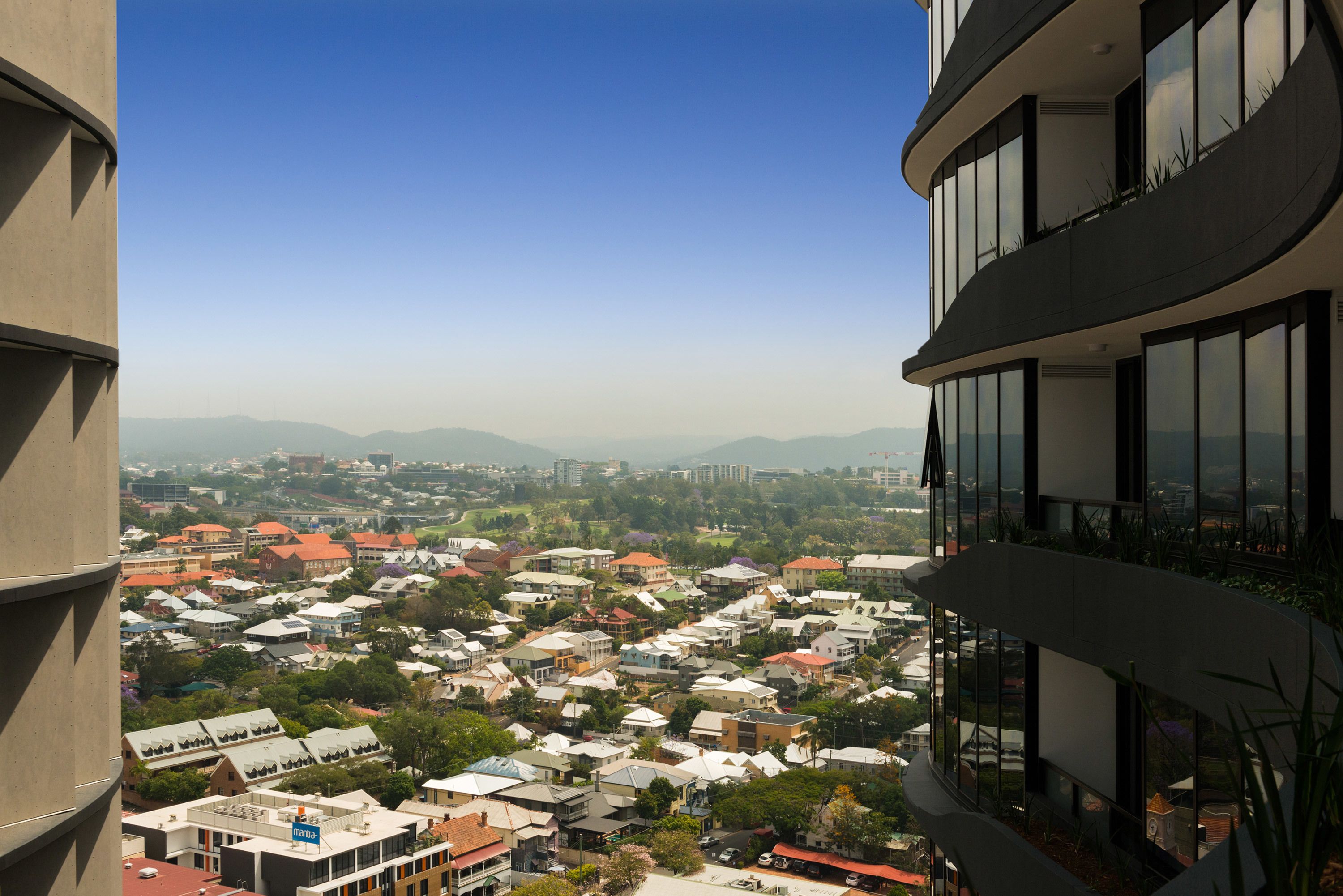A high-rise building with a view of a residential area below.