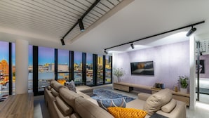A modern living room with a large window, a sofa, a coffee table, and a TV mounted on the wall.