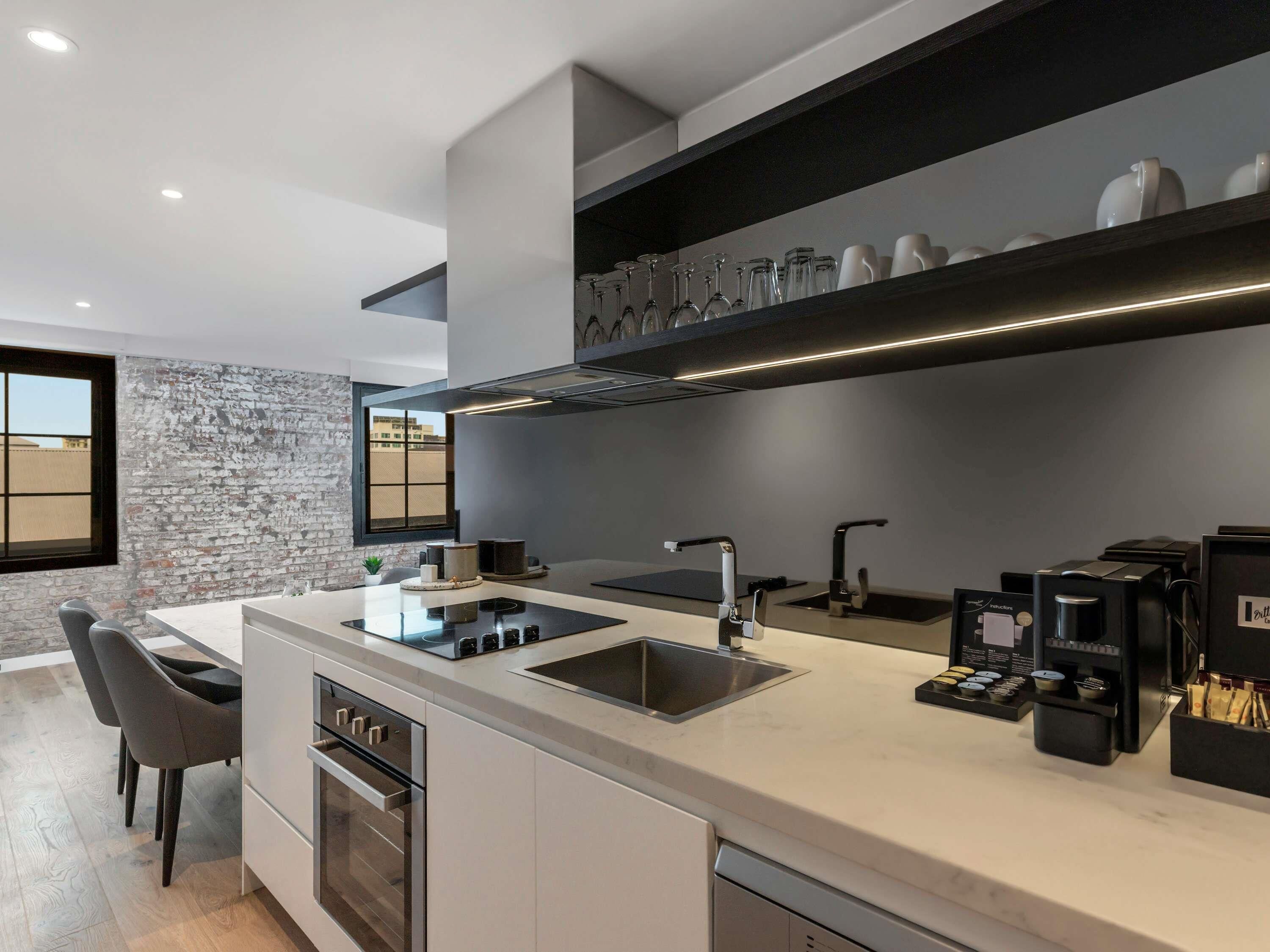 A modern kitchen with a central island, built-in oven, and a coffee machine.