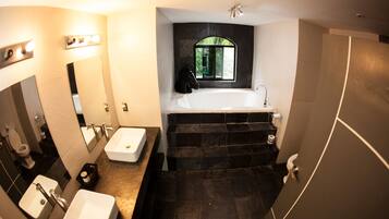 A modern bathroom with a large bathtub, two sinks, and a vanity mirror.