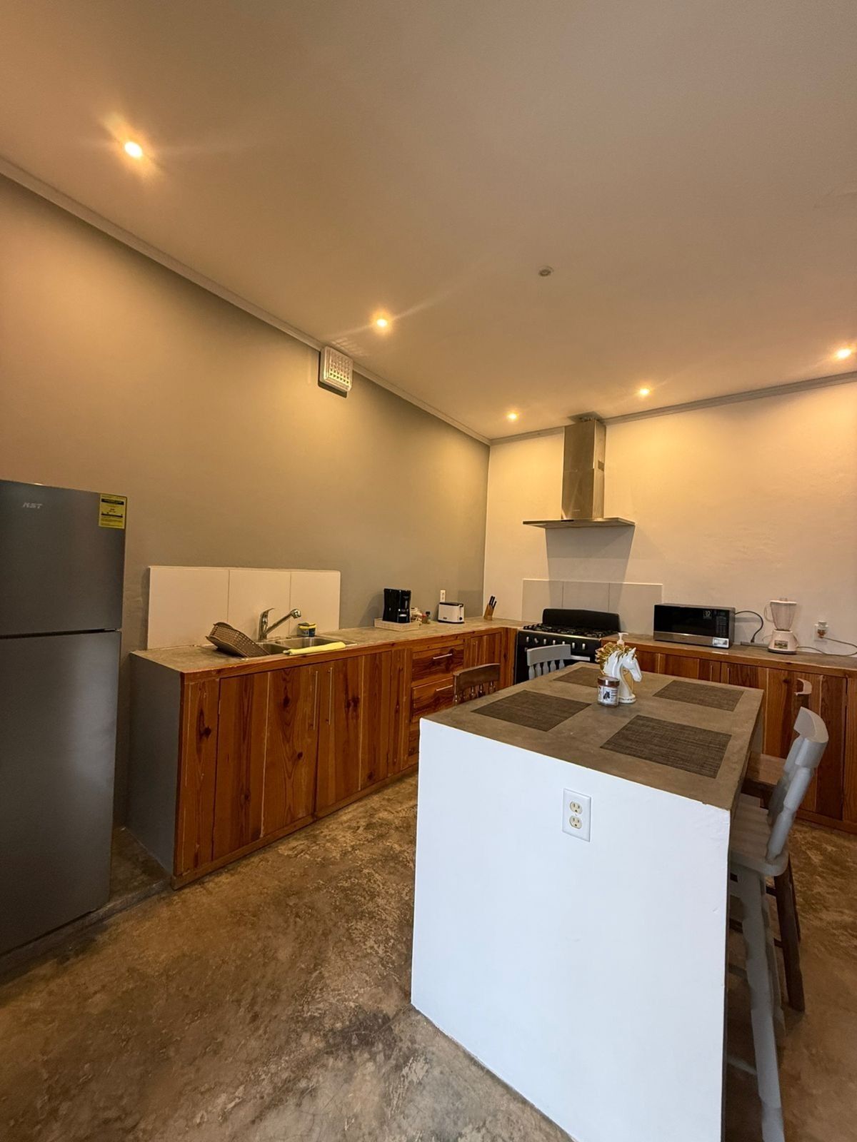 A compact kitchen with wooden cabinets, a central island, and modern appliances.