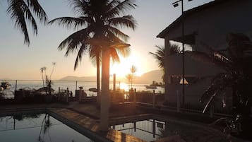 Una piscina al aire libre, sombrillas, sillones reclinables de piscina