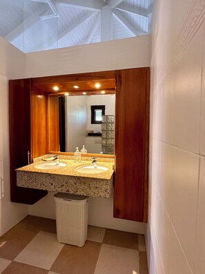 A bathroom with a double sink, a large mirror, and a ceiling skylight. - Blue Bay Beach Villas (Sint Michiel)