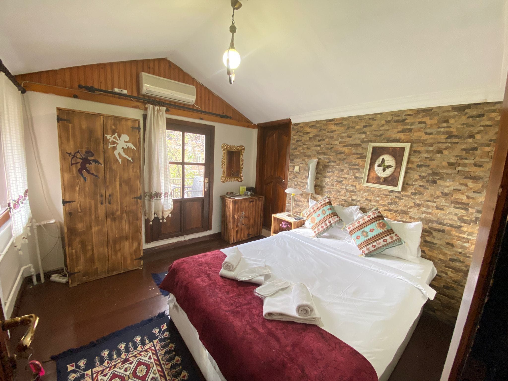 Une chambre avec un grand lit, une armoire en bois et un mur en briques.