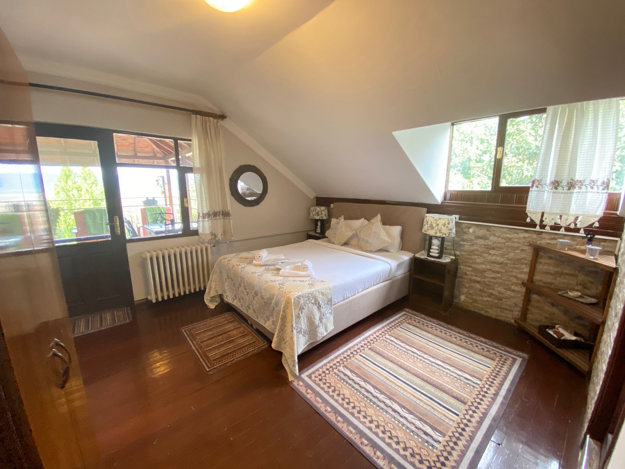 Une chambre à coucher avec un lit, des tables de chevet, un radiateur, une fenêtre et un plancher en bois.