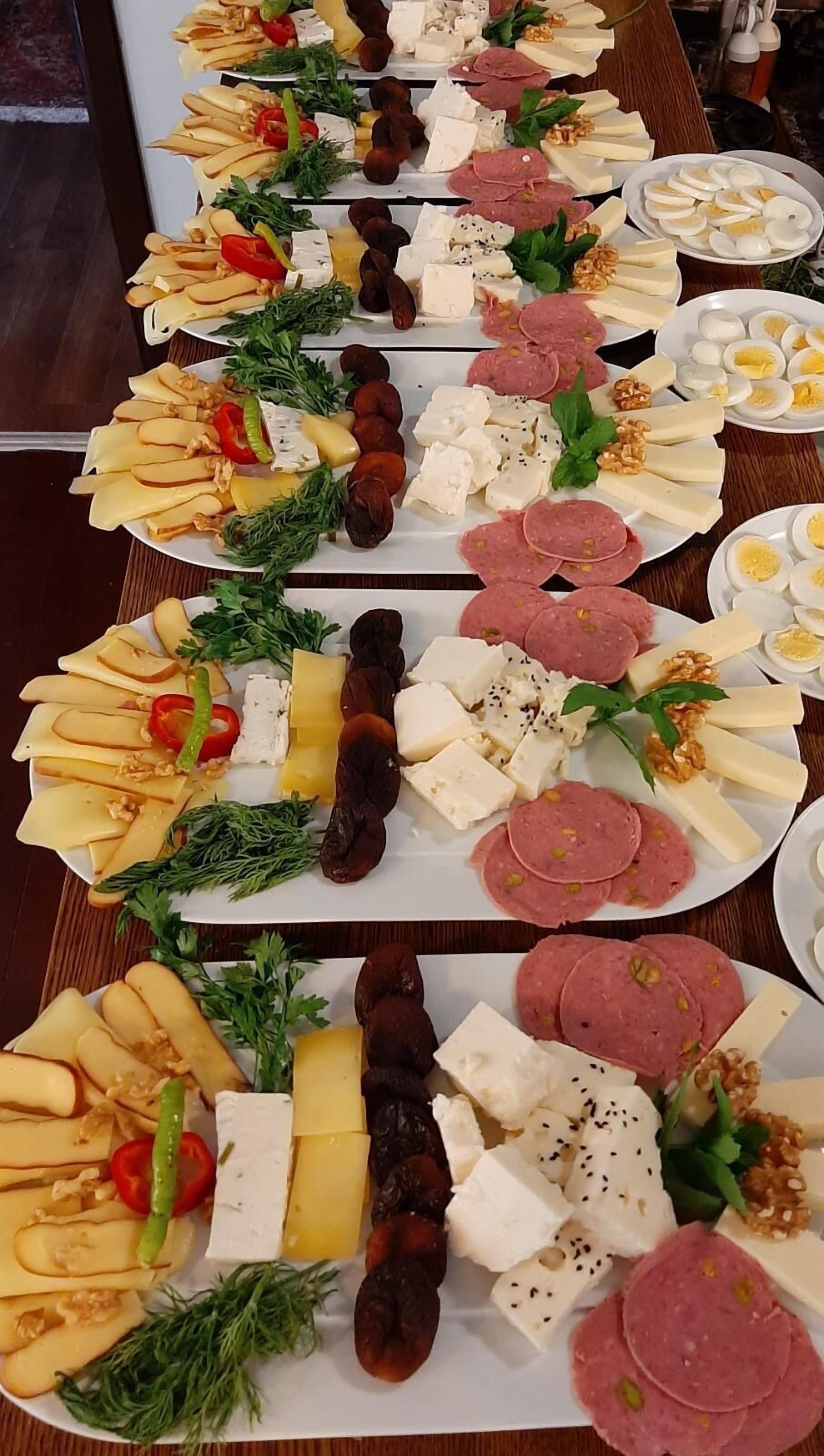 A table with various cheeses, meats, and fruits.