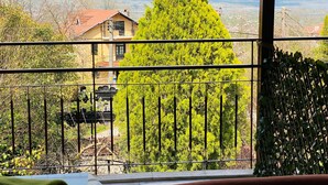 A balcony with a view of a house and a tall tree. - Butik Hotel Masukiye (Kartepe)