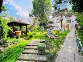 A garden with a wooden pergola, stone steps, and potted plants.