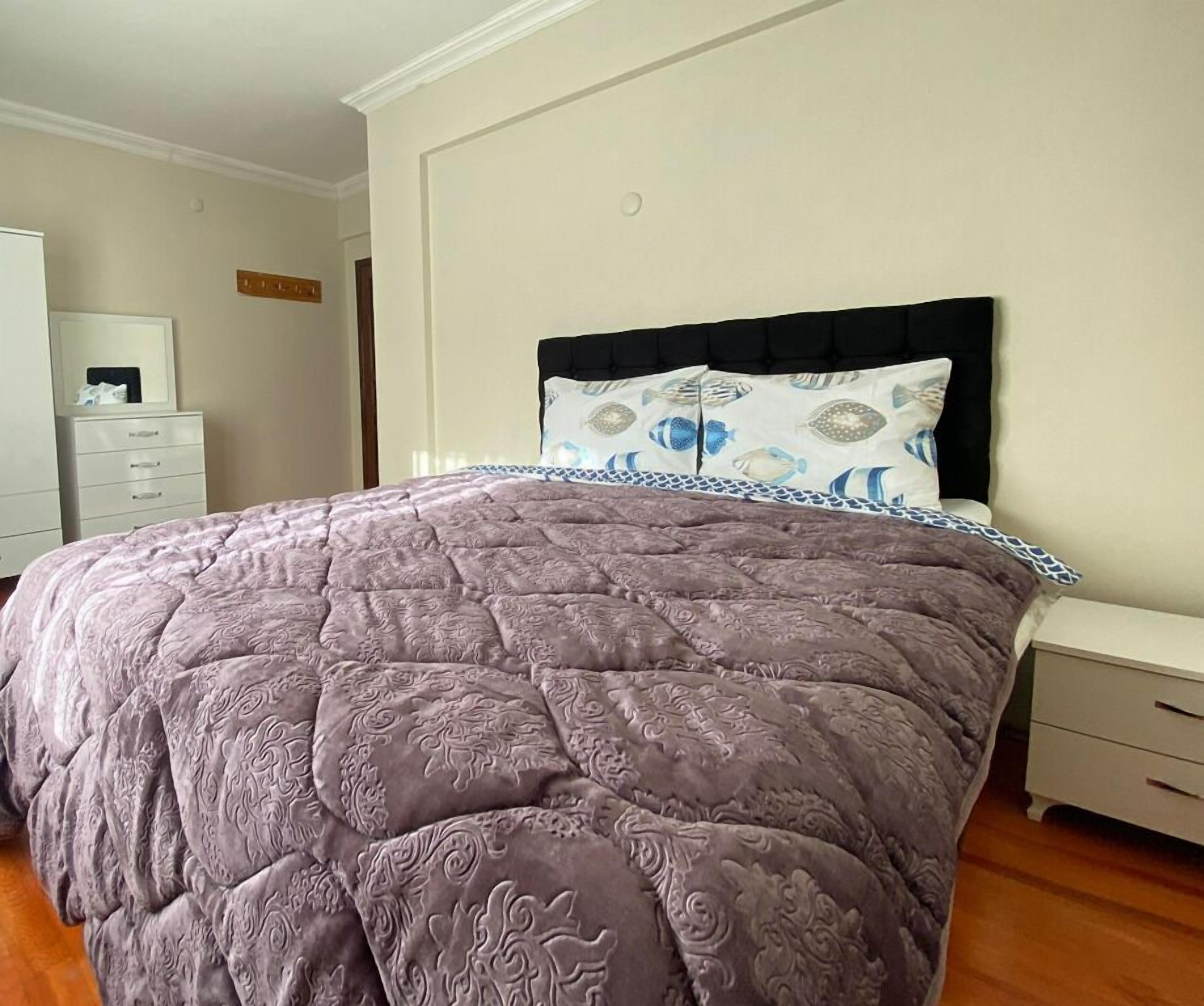 Une chambre à coucher comprenant un lit, une table de chevet, une commode et une étagère fixée au mur.