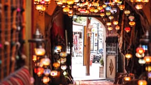 An entrance with a decorative archway adorned with hanging lights, leading to a street view. - Hanzade Cappadocia  (Nevsehir)