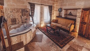 A rustic bathroom with a stone wall, a bathtub, and a wooden ceiling. - Hanzade Cappadocia  (Nevsehir)