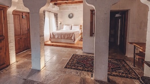 A room with a bed, a wooden door, and a patterned rug. - Hanzade Cappadocia  (Nevsehir)