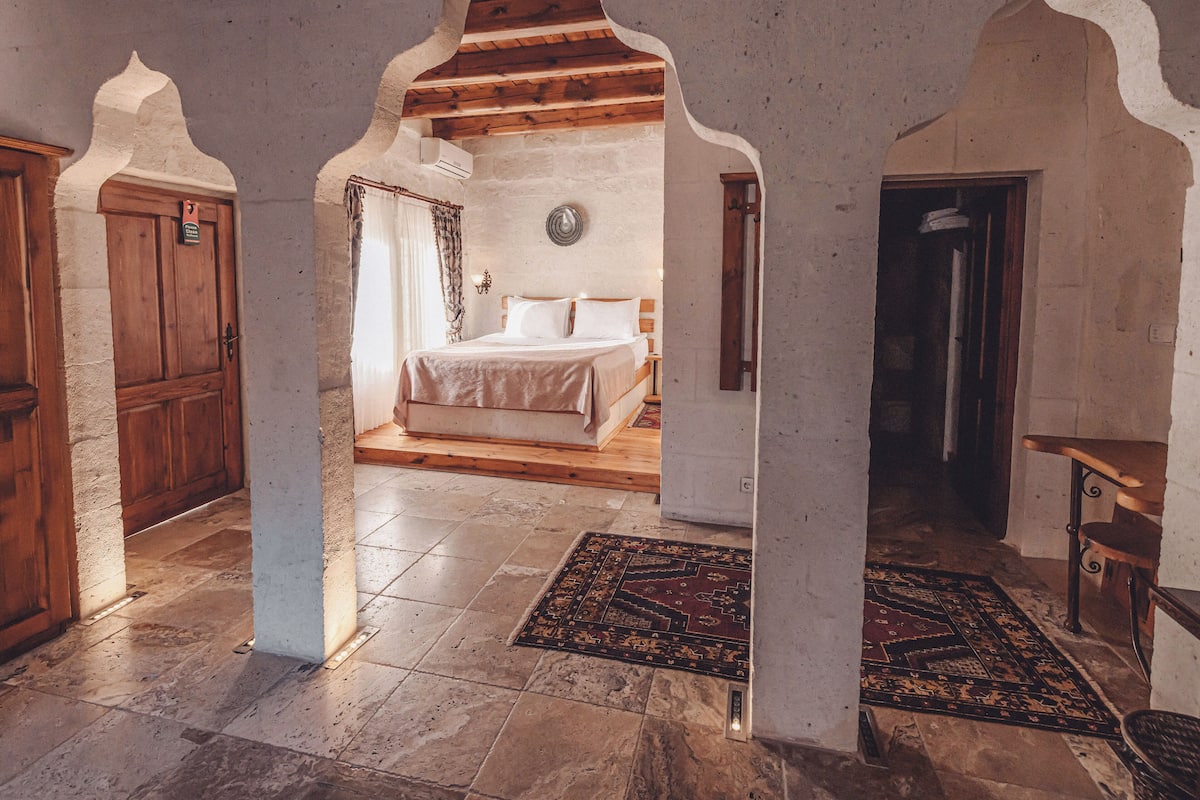 A room with a bed, a wooden door, and a patterned rug.