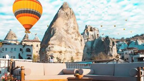 A rooftop terrace with a sofa, table, and potted plants. - Hanzade Cappadocia  (Nevsehir)