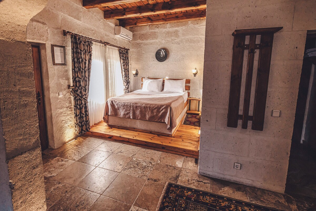 A rustic bedroom with a wooden bed, stone walls, and a sloped ceiling.