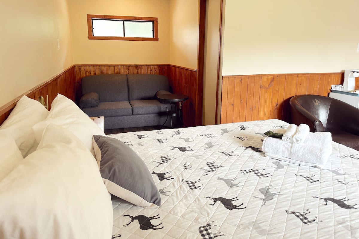 A hotel room with a bed, a sofa, a small table, and a chair.