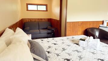 Una habitación de hotel con una cama, un sofá, una mesita y una silla.