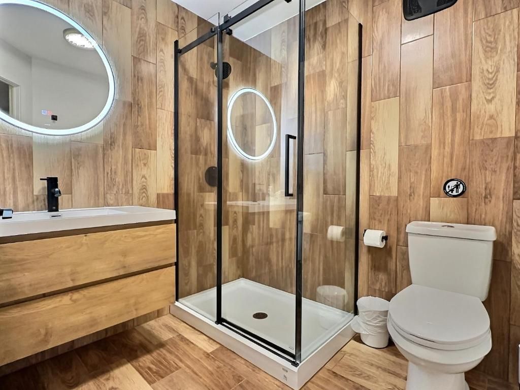 A modern bathroom with a glass-enclosed shower, a white toilet, and a wooden floor.