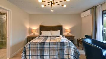 Une chambre à coucher comprenant un lit, deux lampes de chevet, un luminaire au plafond, une chaise et une fenêtre avec des rideaux.