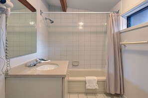 Un baño con lavamanos, espejo, ducha y bañera.