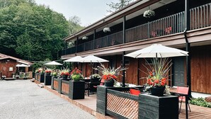 A wooden building with outdoor seating and potted plants. - Hôtel du Lac Lenore (Sainte-Adele)
