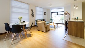 A modern living room with a dining area, a sofa, a coffee table, and a kitchen area with a bar. - Suites Metropoli Edificio Torino (Quito)