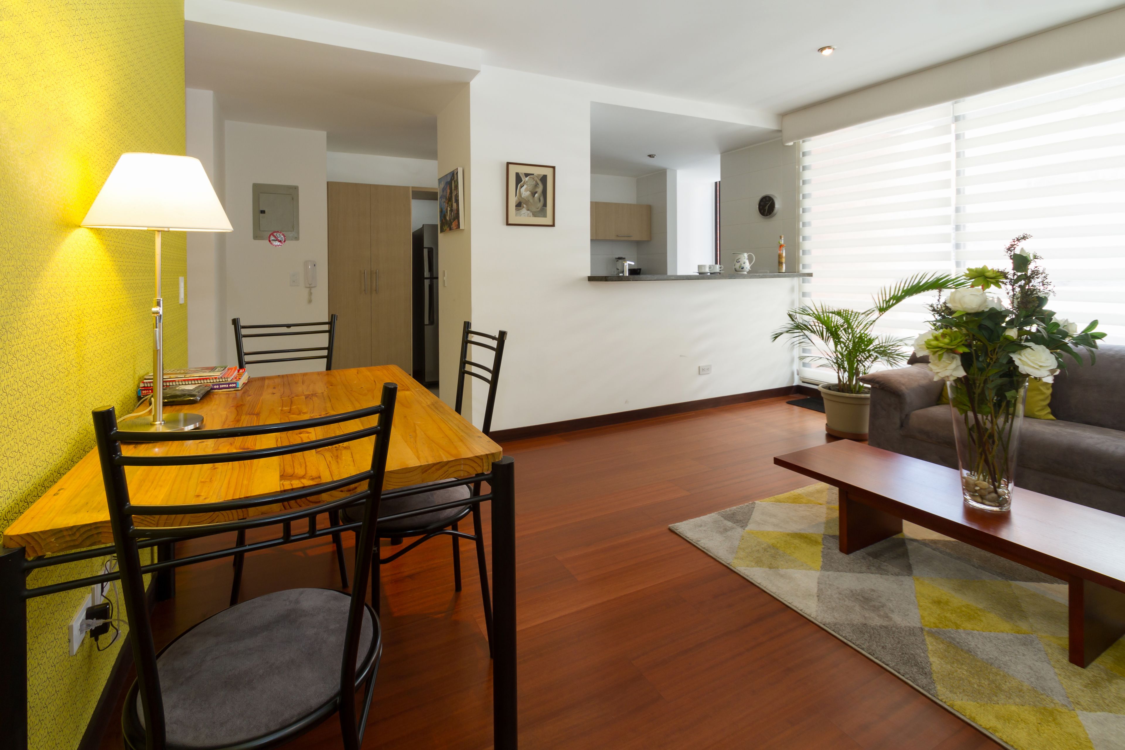 Een eetruimte met een houten tafel en stoelen, een lamp en een vloerkleed.