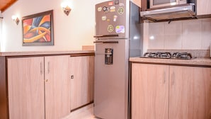 A kitchen with wooden cabinets, a stainless steel refrigerator, a microwave, and a clock on the wall. - Casa 14 (Medellín)