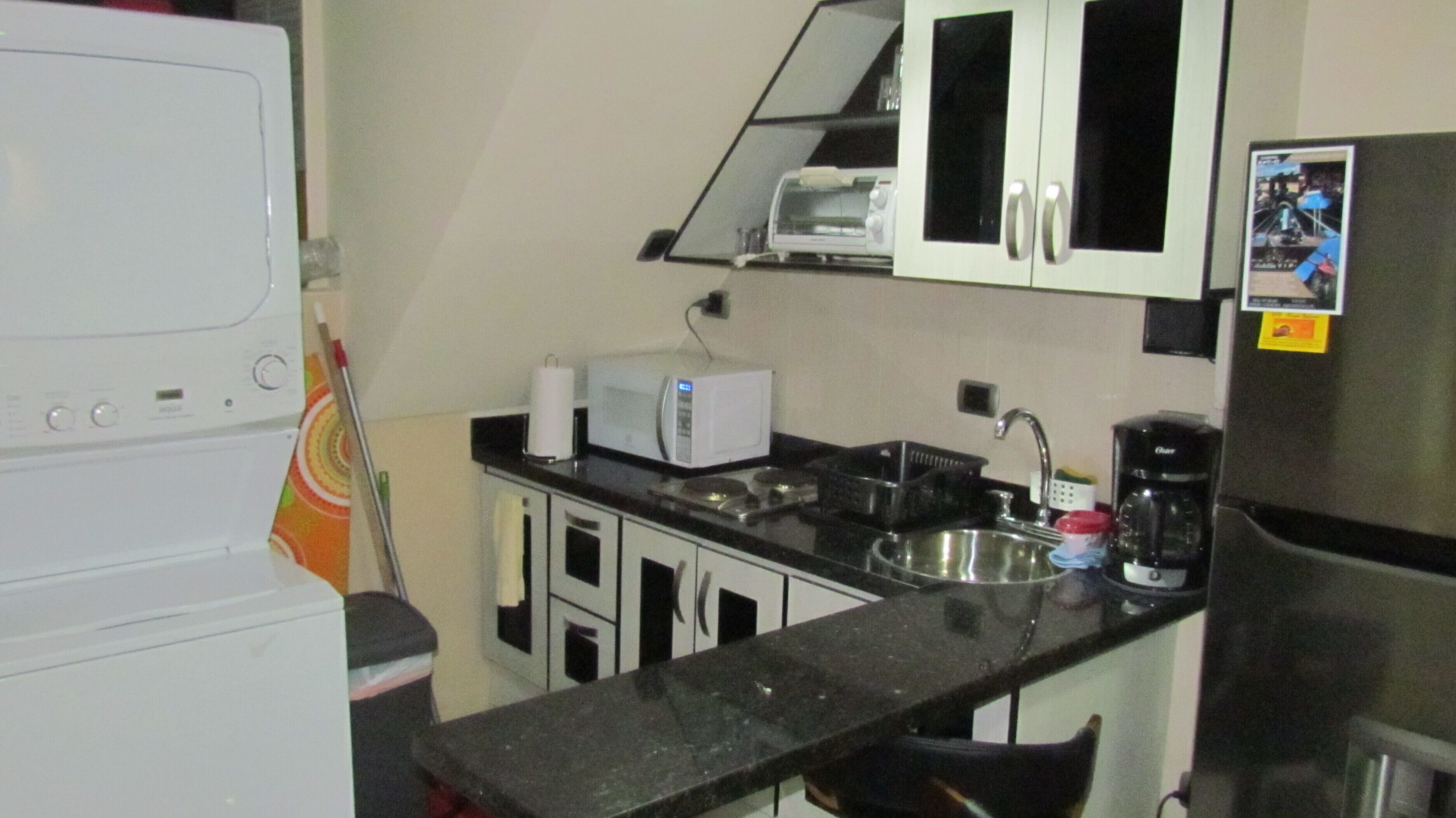 A compact kitchen with a microwave, toaster, sink, and a refrigerator.