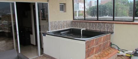 Una cocina con estufa integrada, ventana con vista a la ciudad y piso de baldosas.